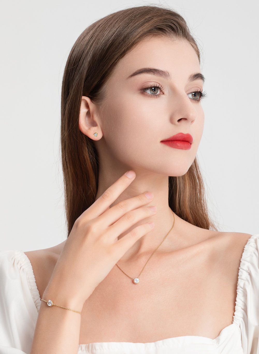 Woman wearing a necklace, earrings, and bracelet on a white background